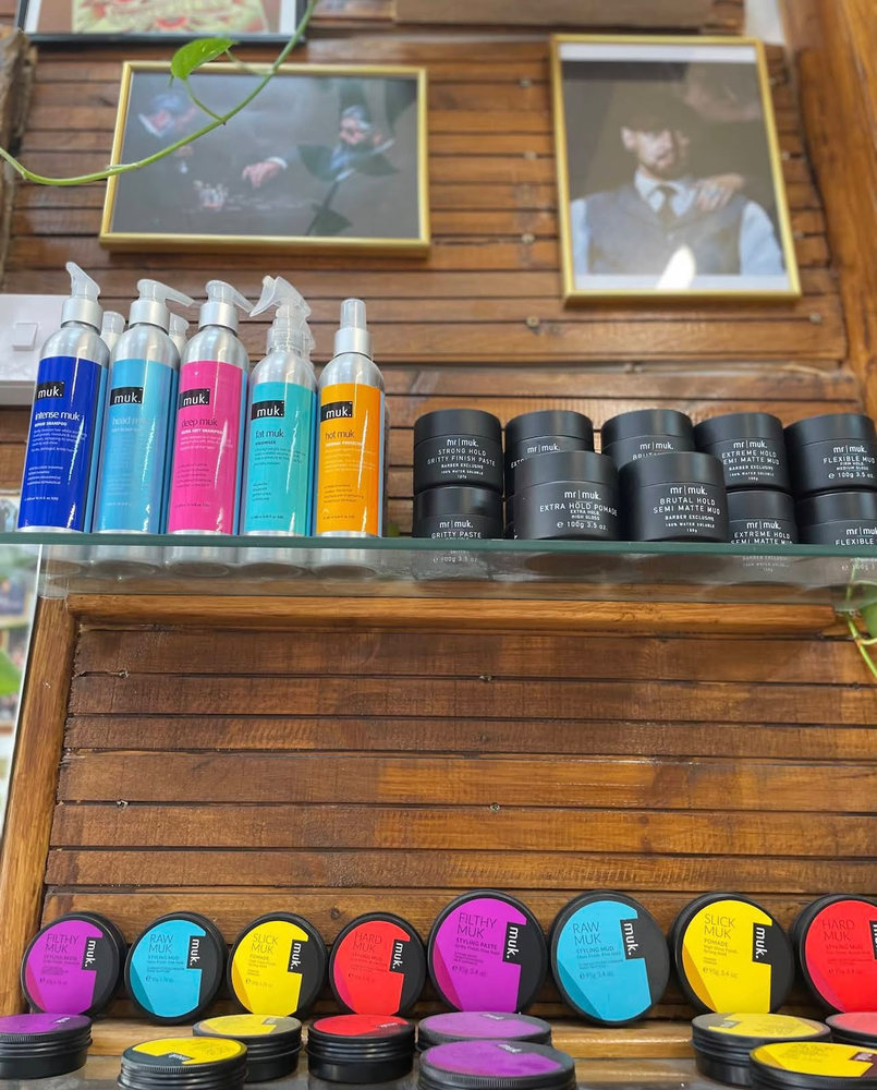 Shelves of muk shampoos and mr muk pomades in bright coloured tins against the wood panelling